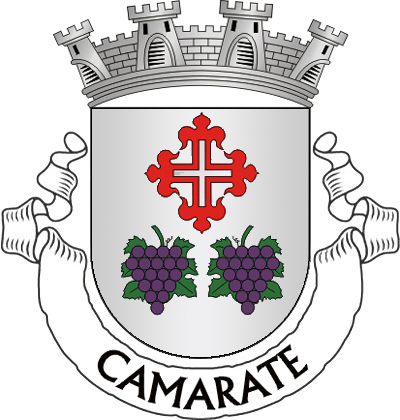 Escudo de prata, cruz flordelisada de vermelho, vazia do campo, acompanhada em ponta por dois cachos de uvas de púrpura, folhados de verde. Coroa mural de prata de quatro torres. Listel branco com a legenda a negro: "CAMARATE". 