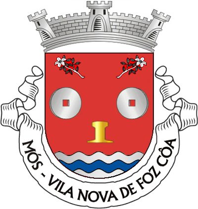 Escudo de vermelho, com duas mós de prata, furadas do campo e um perfil de carril de ouro; em chefe, dois ramos de laranjeira de prata, floridos do mesmo, o da dextra posto em banda e o da sinistra em barra; campanha diminuta de três burelas ondadas de prata e azul. Coroa mural de prata de três torres. Listel branco, com a legenda a negro: "Mós - Vila Nova de Foz Côa".