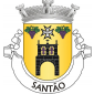 Escudo de ouro, torre sineira de negro, lavrada de prata e aberta do campo, com dois sinos de púrpura; em chefe, cruz da Ordem de Malta, de prata, perfilada de negro, entre dois cachos de uvas de púrpura, folhados de verde. Coroa mural de prata de três torres. Listel branco, com a legenda a negro: «SANTÃO». 