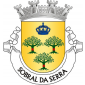 Escudo de ouro, três sobreiros arrancados, de verde, descortiçados de vermelho; em chefe, coroa mariana de azul. Coroa moral de prata de quatro torres. Listel branco, com a legenda a negro: "Sobral da Serra".