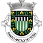 Escudo de verde, quatro palas de prata, chefe de prata carregado de um aqueduto de cinco arcos de negro; bordadura de negro carregada de oito ramos de três laranjas de ouro folhados e ligados por troncos de verde. Coroa mural de três torres de prata. Listel branco, com a legenda a negro: «SANTO ANTÃO do TOJAL».