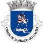 Escudo de azul, cavaleiro vestido de cota de malha brandindo na mão direita uma espada de prata e sustentando no braço esquerdo um escudo amendoado de prata carregado da Cruz de Santiago, de vermelho. O cavaleiro cavalgando um corcel branco. Sob as patas dianteiras do cavalo, um mouro, derrotado, vestido de albornoz e turbante brancos, segurando uma adaga. Coroa mural de prata de cinco torres. Listel branco com os dizeres : " CIDADE DE SANTIAGO DO CACÉM ", de negro.