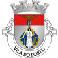 Escudo de prata, com imagem de Nossa Senhora dos Anjos, com vestes brancas e manto de azul realçado de ouro, coroada do mesmo; chefe de vermelho com um açor de sua cor, segurando nas garras um escudete das quinas, de azul carregado de cinco besantes de prata. Coroa mural de prata de quatro torres. Listel branco com letras a negro  " VILA DO PORTO ".