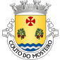 Escudo de ouro, dois ramos de pinheiro de verde, frutados de vermelho, e postos em pala e alinhados em faixa; em chefe, cruz da Ordem do Templo; campanha diminuta ondada de azul e prata de três tiras. Coroa mural de prata de quatro torres. Listel branco, com a legenda a negro: «COUTO do MOSTEIRO».