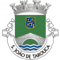 Escudo de verde, ponte de prata de um arco, lavrada de negro, movente dos flancos e de um contra-chefe ondado de prata e azul, debruado de ouro, escudete de púrpura com banda enxaquetada de prata e negro acompanhada em chefe e em ponta de duas flores-de-lis de ouro.
Coroa mural de prata de quatro torres. Listel branco, com a legenda a negro: «SÃO JOÃO DE TAROUCA». 